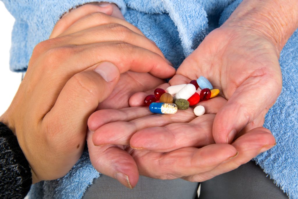Caregiver giving medication to her senior patient